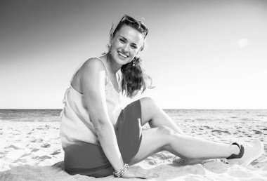 Renkli elbiseli sahilde oturup mutlu genç kadın portresi