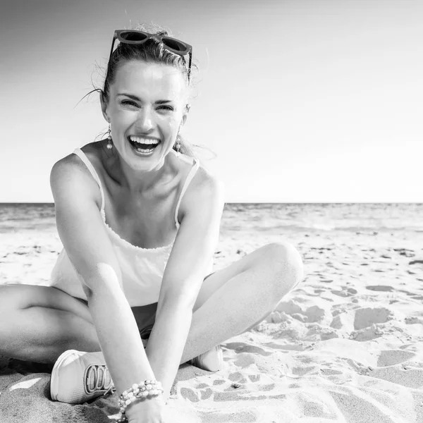 ビーチに座ってカラフルなドレスで笑顔のトレンディな女性 — ストック写真