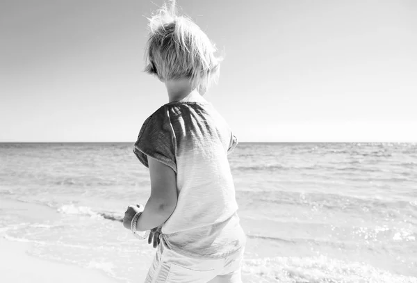 歩いて海岸にカラフルなシャツのモダン ガールの後ろから見てください — ストック写真