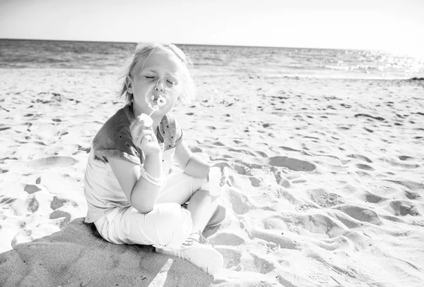 シャボン玉を吹く海岸にカラフルなシャツでトレンディな女の子 — ストック写真