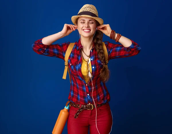 relaxed adventure woman hiker in a plaid shirt  listening to music on blue background