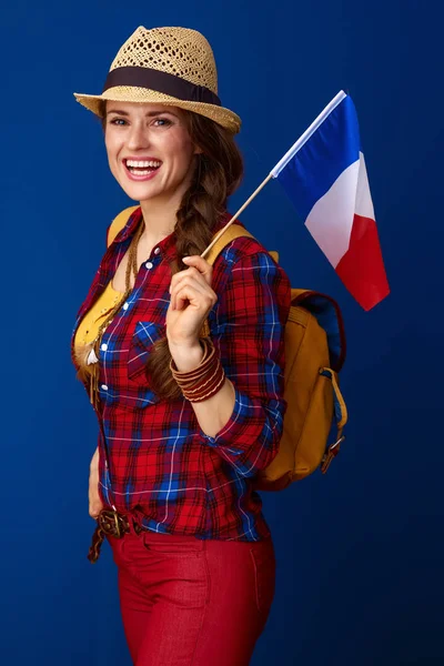 happy adventure woman hiker with backpack and the flag of France on blue background