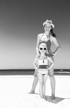 Mutlu modern anne ve kızı mayo daimi deniz kıyısı üzerinde tam uzunlukta portresi