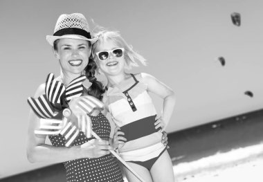  mutlu modern anne ve kızı yel değirmeni oyuncak ile sahil üzerinde parlak mayo