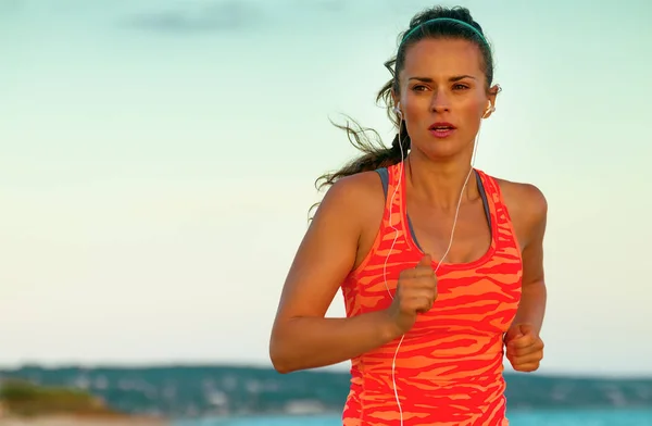 fit active woman in sport style clothes on the beach in the evening jogging
