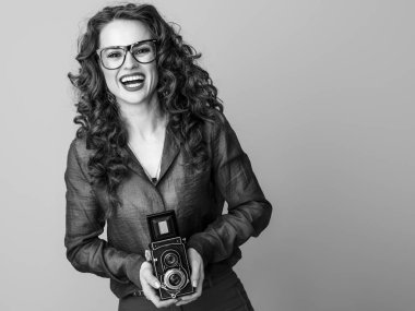 retro fotoğraf makinesi ile uzun dalgalı esmer saçlı gülümseyen genç kadın 