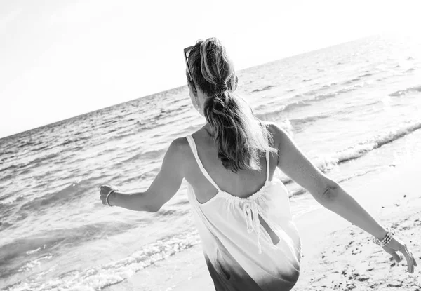 ウォーキング 夜のビーチでドレスを着た若い女性の後ろから見てください — ストック写真
