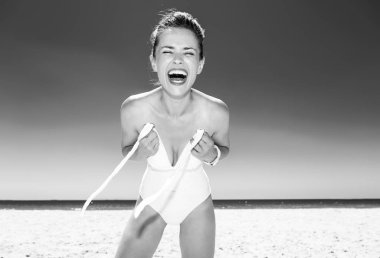 Beyaz kum eğlenceye. Mayo mayo giyinme sahil üzerinde gülümseyen genç kadın portresi