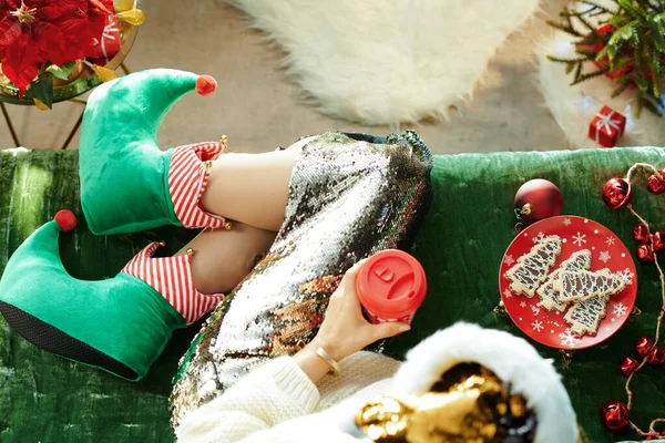 Trendy vrouw in grappig kerstmis elf schoenen op divan — Stockfoto