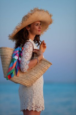 Günbatımında okyanus kıyısında düşünceli modern kadın