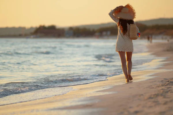 Stylish woman on seacoast at sunset walking — Stock Photo, Image