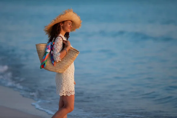 Mujer moderna pensativa de pie en la costa del océano al atardecer —  Fotos de Stock