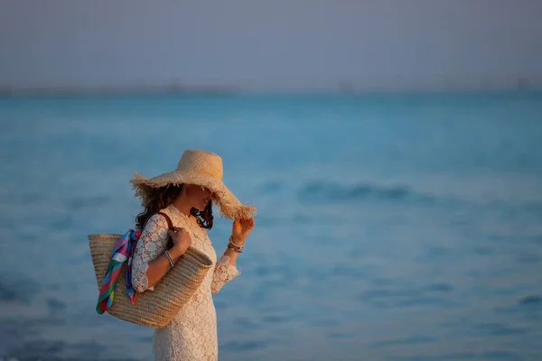 Módní žena středního věku stojící na pobřeží oceánu při západu slunce — Stock fotografie