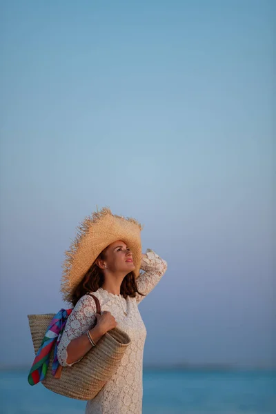 Gün batımında deniz kıyısında rahat bir kadın fotokopi alanına bakıyor. — Stok fotoğraf