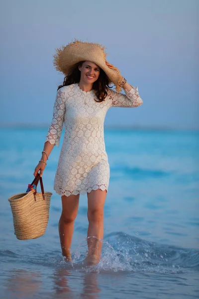 Souriante femme d'âge moyen moderne sur le bord de la mer au coucher du soleil marche — Photo