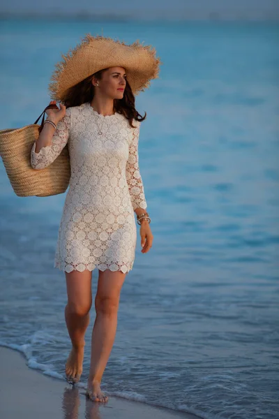 Zamyšlená elegantní žena na břehu oceánu při západu slunce chůze — Stock fotografie
