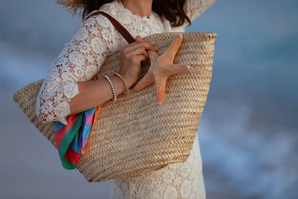 穿着时髦衣服的女人拿着海滩草袋和海星 — 图库照片