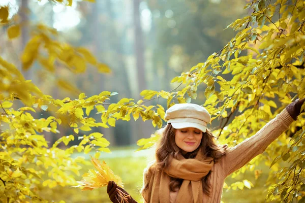 Femme avec des feuilles jaunes à l'extérieur dans le parc d'automne parmi le feuillage — Photo