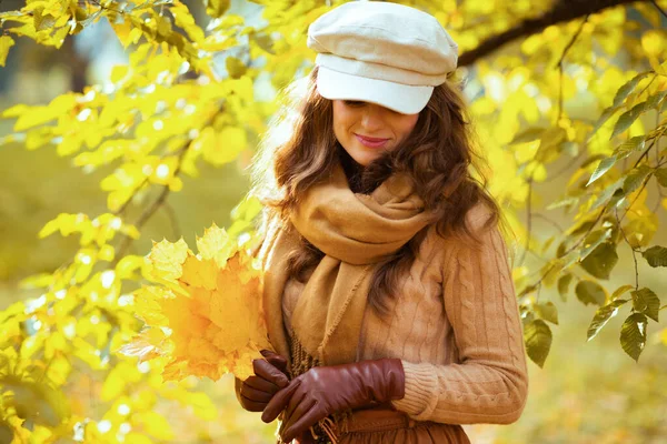 Sarı yapraklı kadın sonbahar parkında yeşilliklerin arasında. — Stok fotoğraf