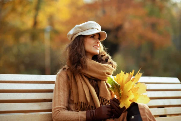 Χαμογελαστή σύγχρονη γυναίκα με κίτρινα φύλλα κοιτάζοντας σε απόσταση — Φωτογραφία Αρχείου