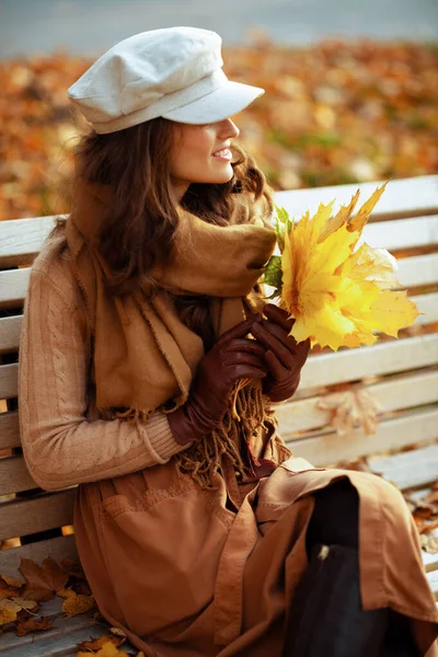 Улыбающаяся молодая женщина с желтыми листьями смотрит вдаль — стоковое фото