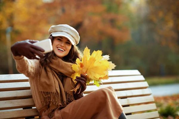 Lächelnde Frau mit gelben Blättern macht Selfie mit Handy — Stockfoto