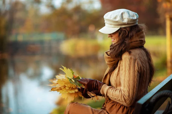 Χαρούμενη μοντέρνα γυναίκα που κοιτάζει κίτρινα φύλλα — Φωτογραφία Αρχείου