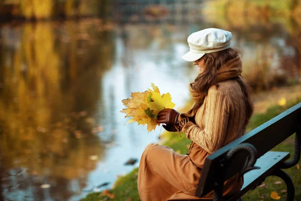 Smiling elegant 40 year old woman looking at yellow leaves — Stock Photo, Image