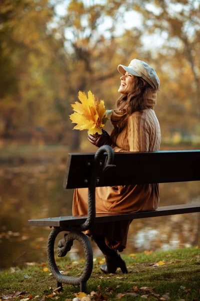 Šťastná elegantní žena se žlutými listy vzhlíží na kopírovací prostor — Stock fotografie