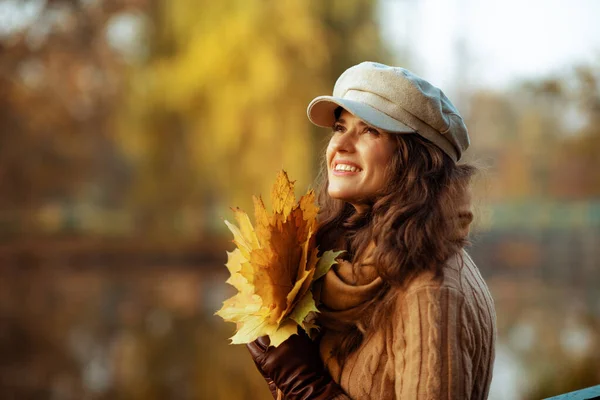 Lächelnde Frau mit gelben Blättern, die zum Kopierraum aufschaut — Stockfoto