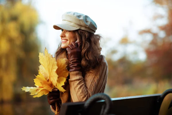 Femme moderne souriante avec des feuilles jaunes parlant sur téléphone portable — Photo