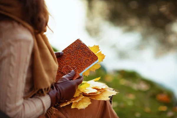 Primer plano de la joven con cuaderno y hojas amarillas — Foto de Stock