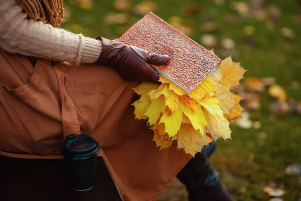 Closeup on woman with notebook, yellow leaves and cup of coffee — Stock Photo, Image