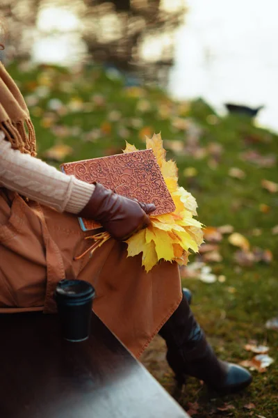 Closeup on woman with notebook, yellow leaves and cup of coffee — Stock Photo, Image