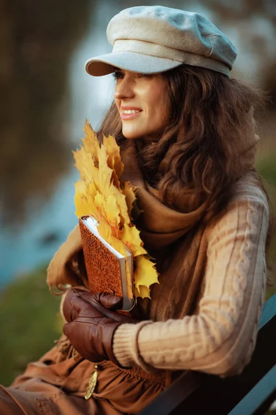 Smiling stylish woman with notebook and yellow leaves — Stock Photo, Image