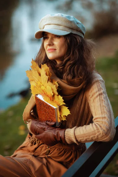 Mulher na moda pensativo com caderno e folhas amarelas — Fotografia de Stock