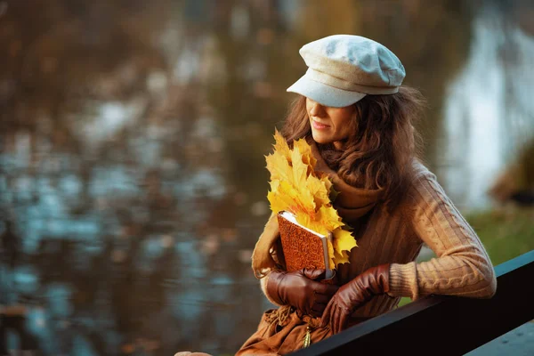 Pensive young woman with notebook and yellow leaves — Stock Photo, Image