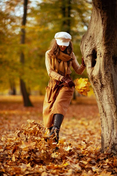 Mulher elegante fora no parque de outono chutando folhas — Fotografia de Stock