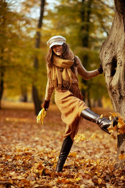 Donna moderna all'aperto in autunno parco calci foglie — Foto Stock