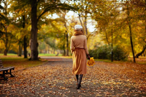 Femme avec des feuilles jaunes marchant à l'extérieur dans le parc d'automne — Photo