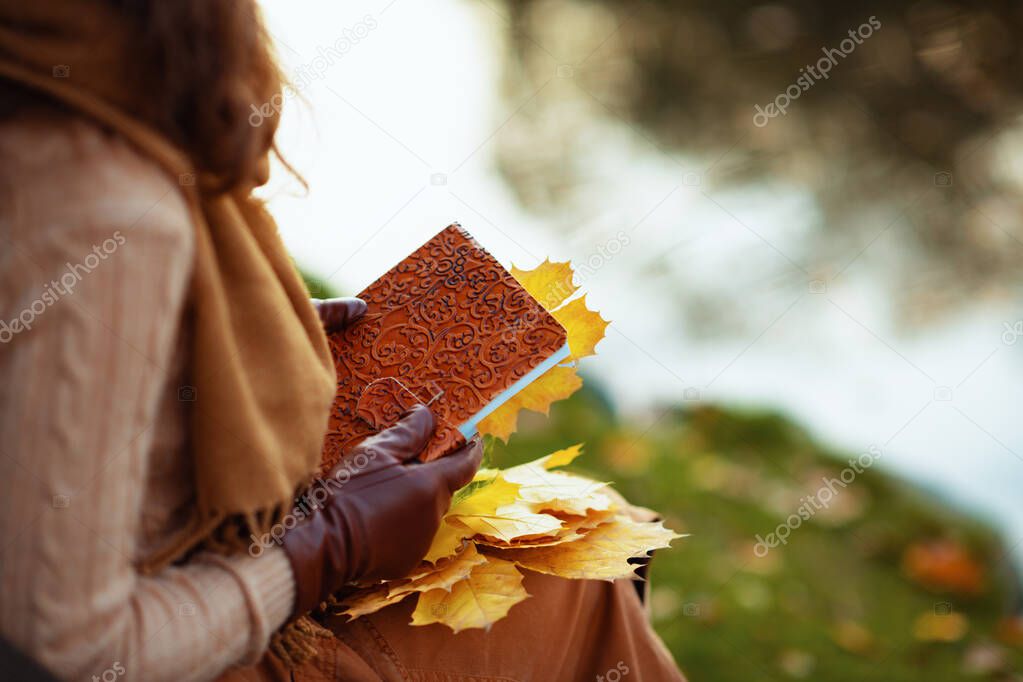 Closeup on young woman with notebook and yellow leaves