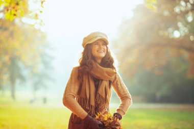 Sonbahar parkında sarı yapraklar kusan bir kadın.