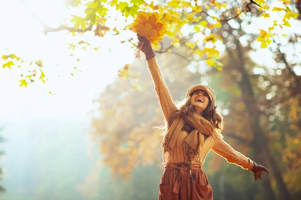 Mujer feliz con hojas amarillas regocijándose afuera en el parque de otoño — Foto de Stock