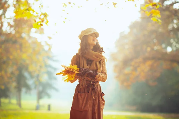 Mujer sonriente con hojas amarillas al aire libre en el parque de otoño —  Fotos de Stock