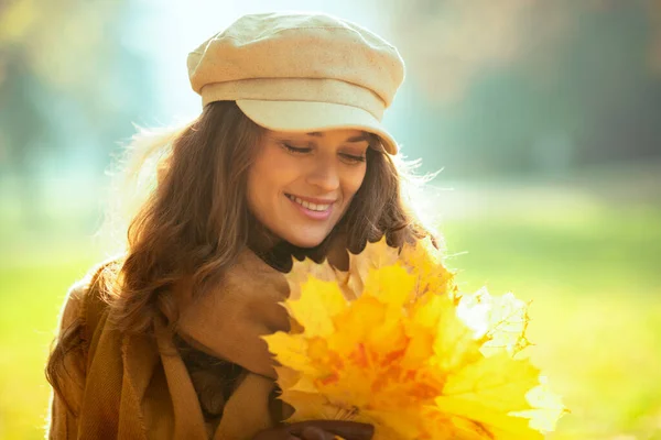 Entspannte moderne Frau mit gelben Blättern draußen im Herbstpark — Stockfoto