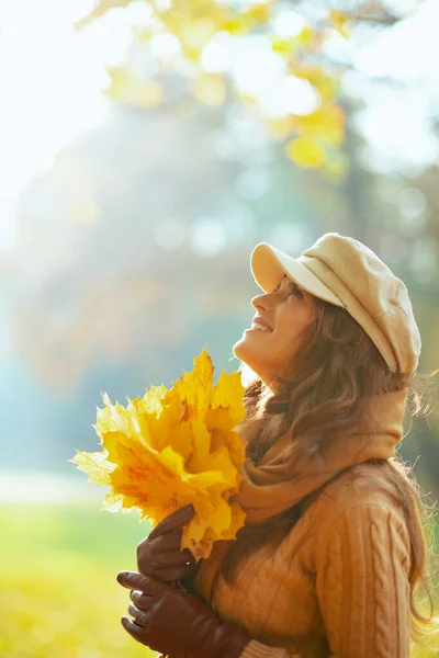 Χαμογελαστή γυναίκα με κίτρινα φύλλα κοιτάζει ψηλά στο χώρο αντίγραφο — Φωτογραφία Αρχείου