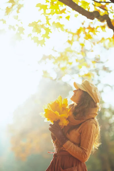 Ευτυχισμένη γυναίκα με κίτρινα φύλλα κοιτάζει ψηλά στο χώρο αντίγραφο — Φωτογραφία Αρχείου
