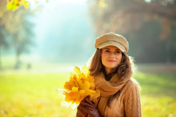 Zamyślona nowoczesna kobieta z żółtymi liśćmi na zewnątrz jesiennego parku — Zdjęcie stockowe