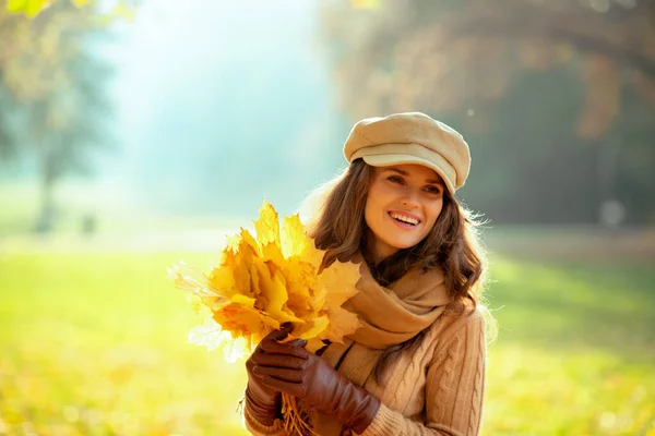 Mujer con hojas amarillas mirando al aire libre en el parque de otoño — Foto de Stock