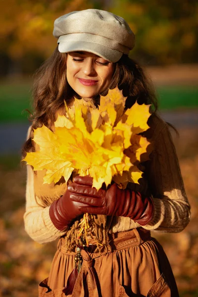 Avslappnad kvinna med gula löv utomhus i höstparken — Stockfoto